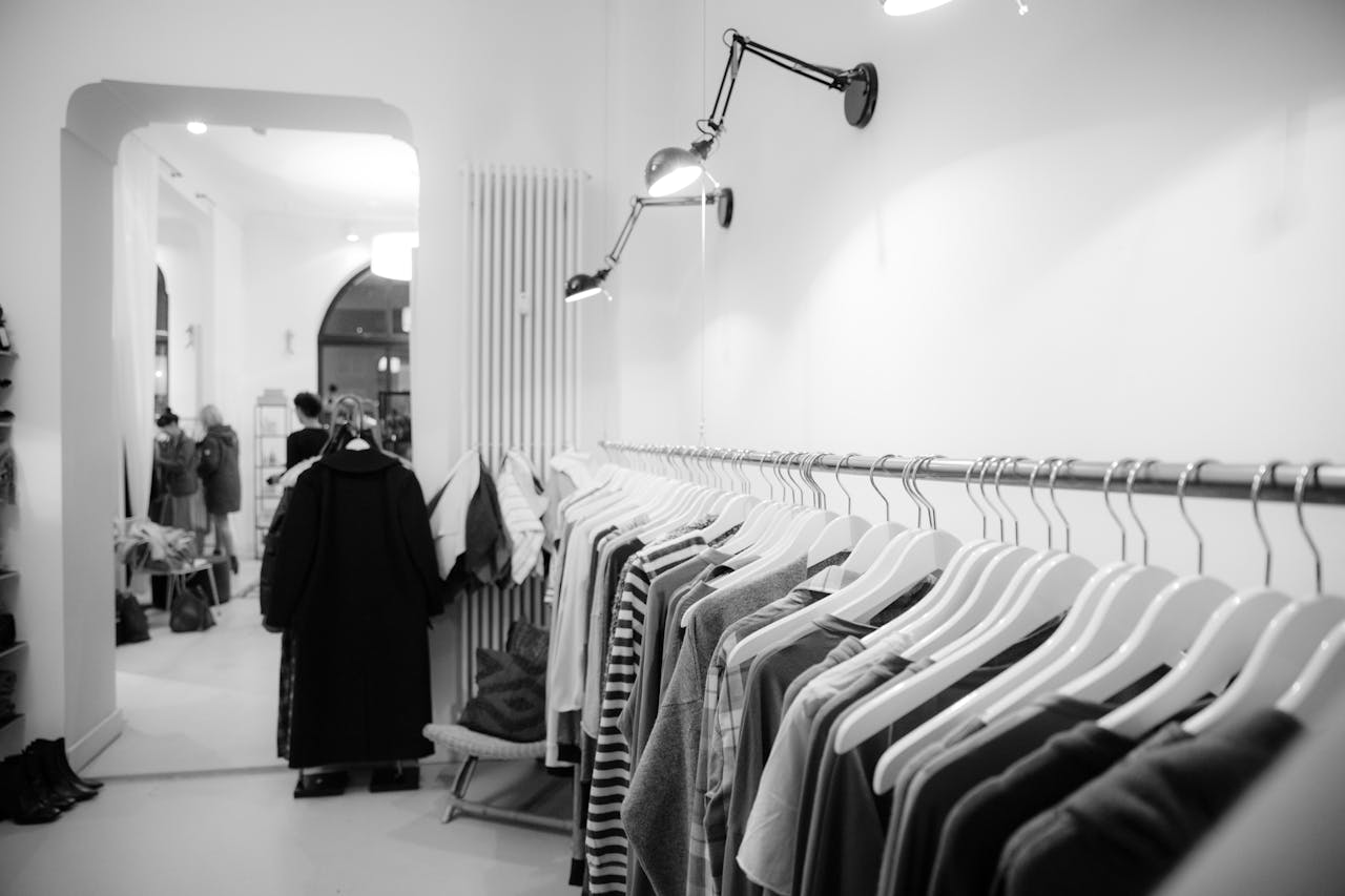 Nos Offres Stylish black and white interior of a boutique with clothes on racks, showcasing modern fashion.